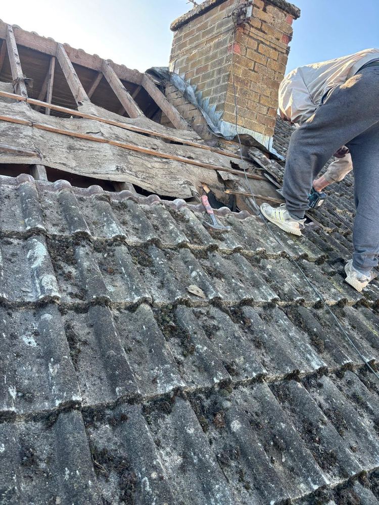Old concrete tiles being stripped off a roof