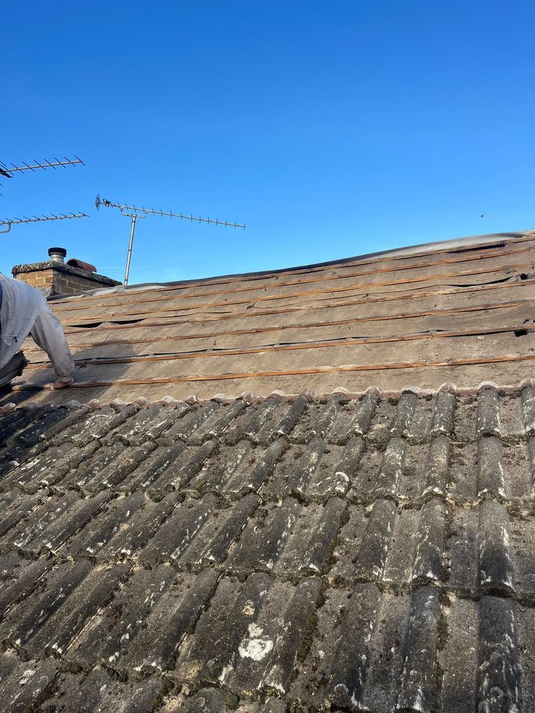 Roofer stripping a tiled roof back to the timbers